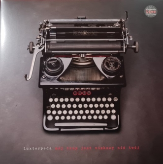 Okładka płyty zespołu Luxtorpeda. Okładka albumu ma szare, raczej jednolite tło, na którym usadowiła się stara, zachwycająca, tradycyjna maszyna do pisania. Maszyna jest w samym środku okładki. na wałku, dzięki któremu w maszynę wkręcało się kartę papieru, widnieje znaczek/ logo Luxtorpedy.
